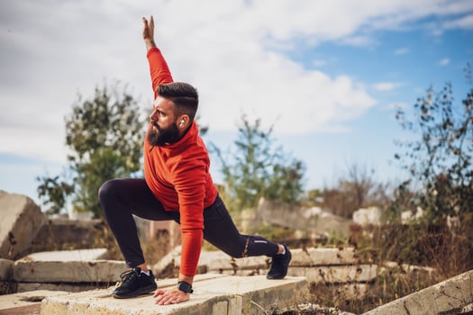 Adult man is exercising outdoor on sunny day. He is stretching his body. photo