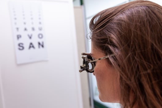 beautiful woman testing new auxiliary lenses with phoropter during an eye examination photo