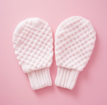 AI generated two knitted white mittens on a pink surface photo