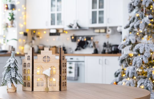 Key and tiny house of a small size on cozy home with Christmas decor on table of festive white kitchen. Gift for New Year. Insurance, moving to new house, mortgage, rent and purchase real estate photo
