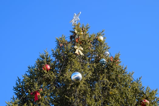 Decorations New Year tree. Tinsel and toys, balls and other decorations on the Christmas Christmas tree standing in the open air. photo
