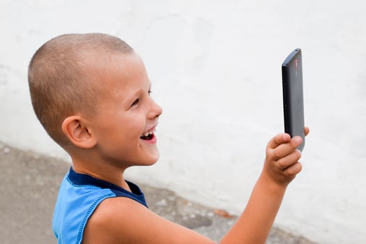 Child with a smartphone. A little boy shoots video on a smartphone. photo