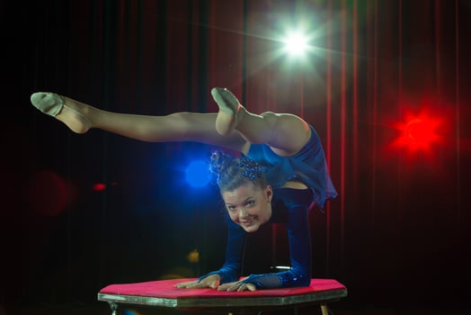 A girl with a flexible body. Performs a circus artist. Circus gymnast. Balancing act. The child performs an acrobatic trick photo