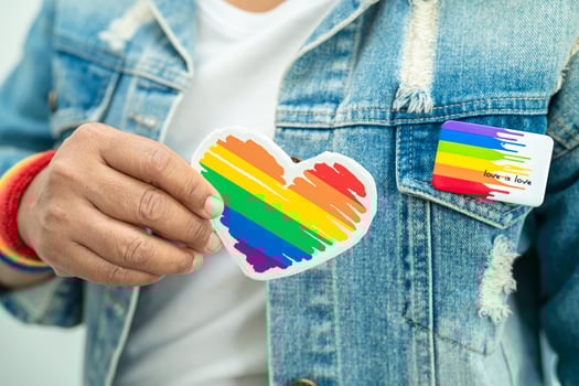 Asian lady wearing rainbow flag wristbands and hold red heart, symbol of LGBT pride month celebrate annual in June social of gay, lesbian, bisexual, transgender, human rights. photo