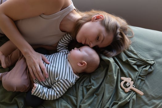 mother and newborn baby are lying on the bed in the bedroom opposite the window photo