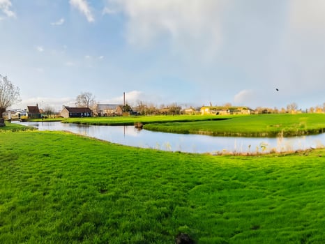 Village of Amsterdam Netherlands, view of river and field grass photo