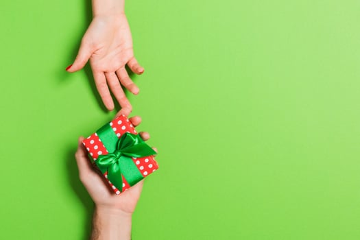 Top view of a man and a woman holding a gift box on colorful background. Love and relationship concept. Copy space photo