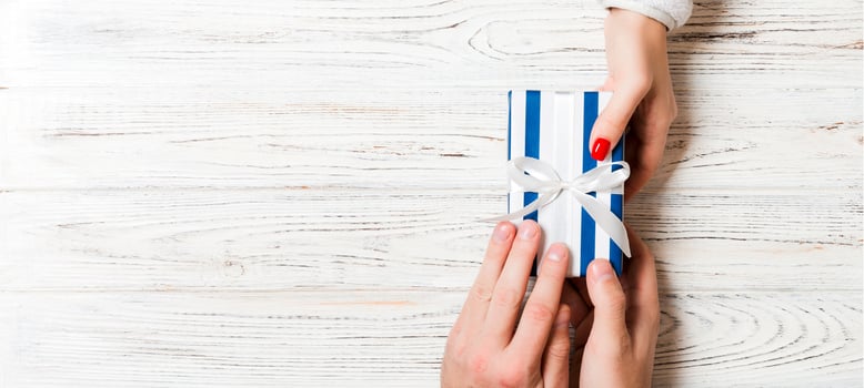 Top view of two people sharing a present on wooden background. Holiday and surprise concept. Copy space photo