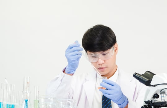 Portrait asian man student scientist Wearing a doctor gown in the lab looking hand at chemist. caused by mixing reagents in scientific research laboratories with test tubes and microscope on the table photo