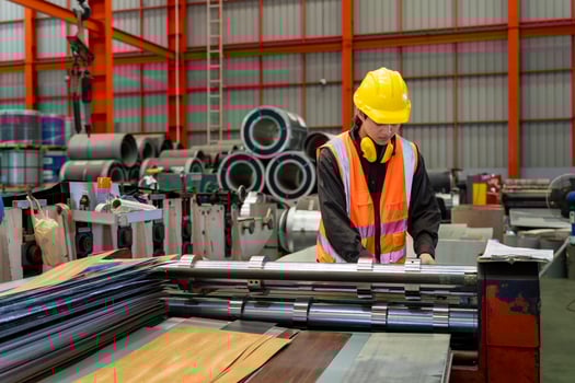 Asian industrial worker is checking the setup value of metal sheet roll forming machine inside roof factory for safety industry construction photo