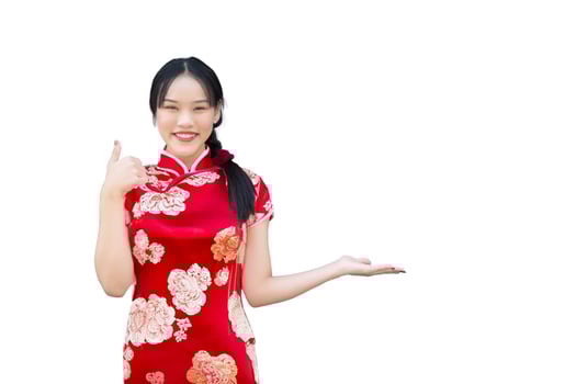 Asian woman with long hair who wears red Cheongsam dress in Chinese new year theme while her hand shows to present something and showing hand as thump up happily while isolated on white background. photo
