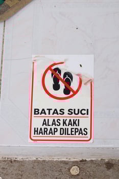 A warning sign stuck to the ceramic floor means sacred boundary, please remove footwear photo