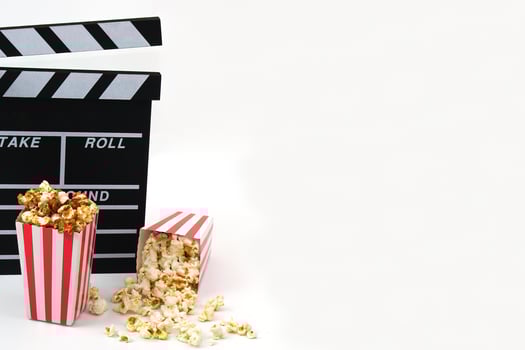 Clapperboard or movie slate black color with popcorn on white background. Cinema industry, video production and film concept. photo