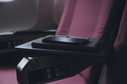 Attractive asian female passenger of airplane sitting in comfortable seat listening music in earphones while working at modern laptop computer with mock up area using wireless connection on board. photo