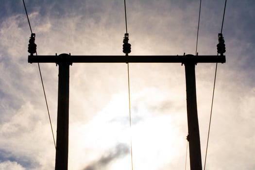 Wooden utility poles in silhouette with electricity wires on a cloudy sky during sunset. photo