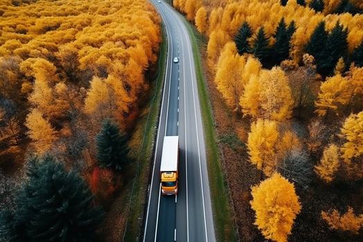 AI generated Arial view of heavy truck on a narrow twisting road. Autumn colorful trees by the sides of the road. photo
