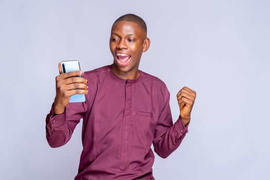 happy black guy in authentic african costume using mobile phone, white background, copy space photo