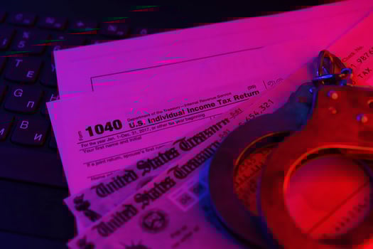 US Tax refund check and handcuffs on computer keyboard close up photo