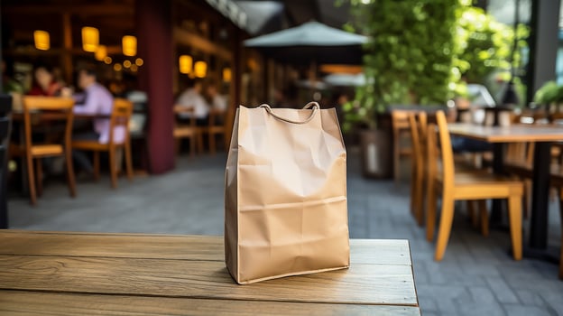 AI generated Food Delivery blank paper bag on the wooden, and blurry restaurants in background photo