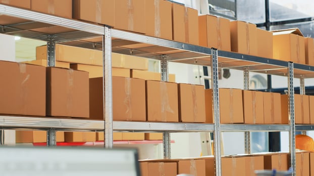 Empty warehouse with computer and cardboard boxes on racks, products prepared to sell for retail store transportation. Storage room with device and merchandise packages, distribution goods. photo