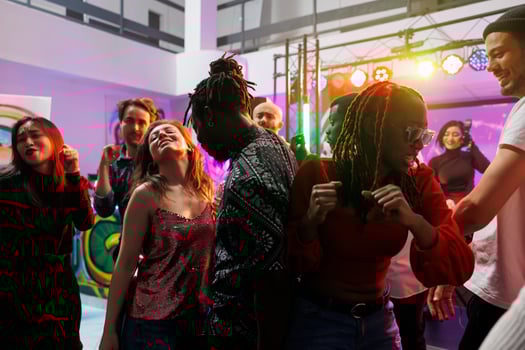 Happy friends group dancing and having fun on crowded dancefloor while attending gathering in nightclub. Cheerful diverse people jumping and moving to music beats in club photo