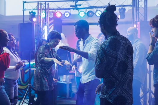 Cheerful dancers doing dance battle while having fun and partying with friends in nightclub. Smiling carefree man and woman showing moves on club dancefloor with spotlights photo
