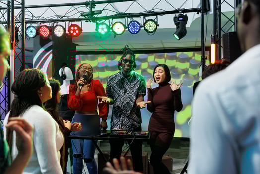 Smiling cheerful women singers and man dj playing on stage at live music concert in nightclub. Carefree energetic musicians band performing at club party social gathering photo