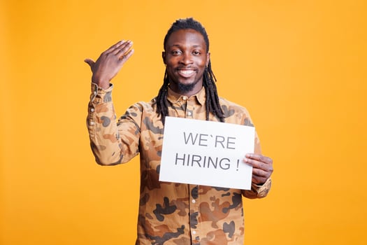 African american manager holding paper to make job offer in front of camera, hiring perfect candidate for career opportunity. Hr employee asking people to attend job interview in studio photo