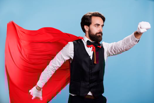 Professional person wears red cape in front of camera, posing with cartoon mantle for strength and force. Powerful man feeling strong while he wears fantasy costume as superhero. photo