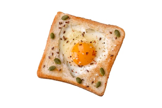 Heart shaped fried egg in bread toast with sesame seeds, flax seeds and pumpkin seeds on a black plate photo