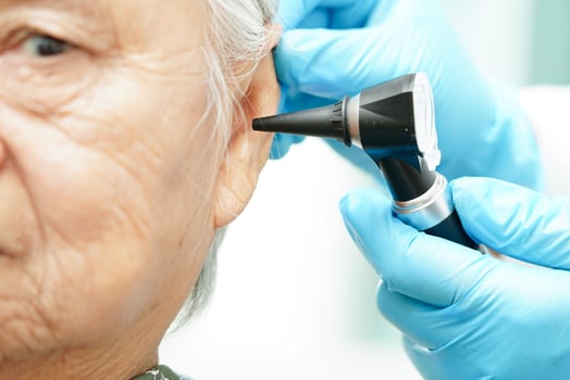 Otolaryngologist or ENT physician doctor examining senior patient ear with otoscope, hearing loss problem. photo