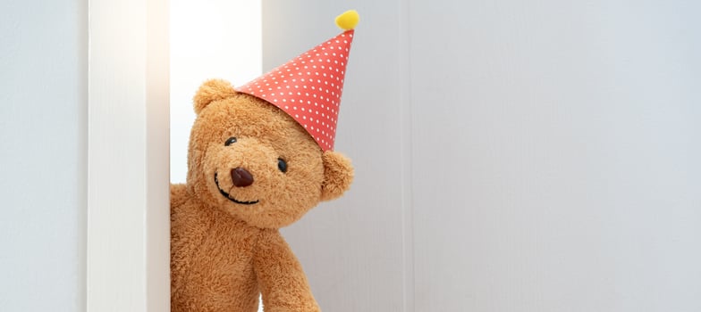 Cute brown Teddy bear toy sneak behind the door and surprise to congratulate the special day holiday festivals. game child, day care, welcome, kid day, shy childhood, party funny, stuffed doll photo