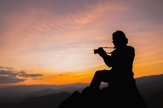 Silhouette of a photographer on top of a mountain at sunset photo