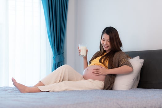 Portrait of beautiful asian pregnant woman drinking milk in bedroom at home photo