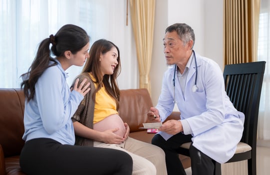 Asian pregnant woman and her friend visit gynecologist doctor at medical clinic for pregnancy consultant. The doctor explains the results of the health examination of the baby and mother. photo
