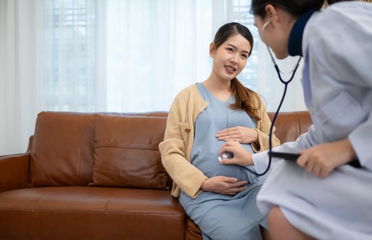Asian pregnant woman visit gynecologist doctor at medical clinic for pregnancy consultant. Doctor examine pregnant belly for baby and mother healthcare check up. photo