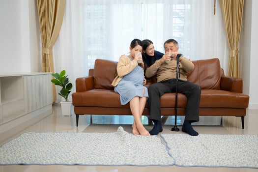 A happy family sits on the sofa in the living room, Father and daughter are pregnant drinking milk and talk to each other. photo
