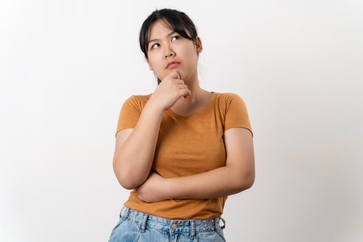 The curious thoughtful young Asian woman looks pensively standing on white background. photo