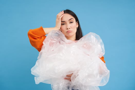 Eco activism and recycling. Young asian woman with bothered face, tired of ignorance for environment, holding plastic waste, looks annoyed photo