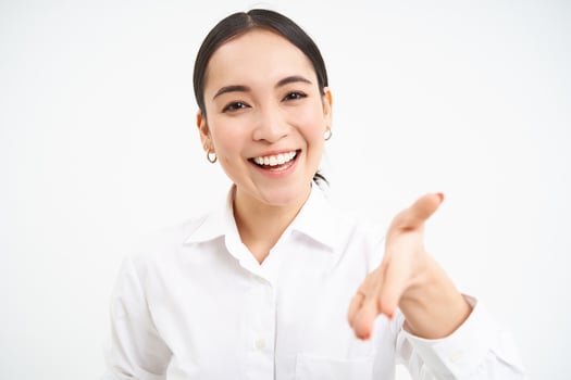 Asian businesswoman extends hand for handshake, team leader introduces herself and smiles friendly, stands confident on white isolated background photo
