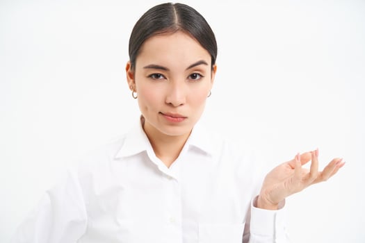 Portrait of skeptical asian woman, looks unamused and serious at camera, stands isolated on white background photo