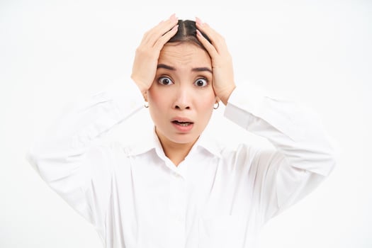 Portrait of anxious and worried asian businesswoman grabs head in hands, panics, looks nervous and desperate, stands over white background photo