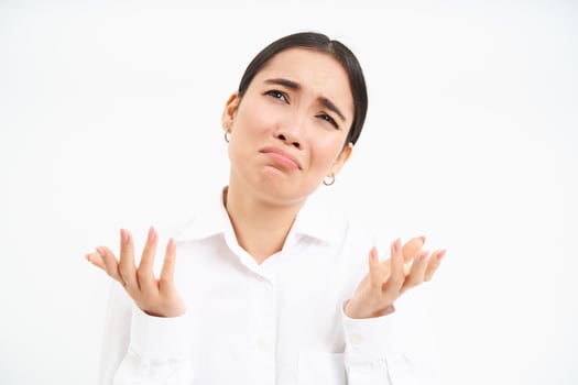 Upset asian woman looks up with desperate and sad face, complains to Lord, stands over white background photo