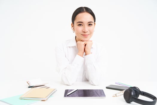 Office and profession. Portrait of successful businesswoman sits behind table with digital tablet, headphones, smartphone and documents, smiling at camera photo
