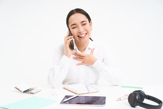 Image of asian woman in office, talks on cellphone, discuss work with client on mobile phone, sits over white background photo