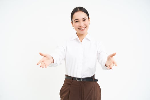 Friendly businesswoman stretches hands with warm welcome, invites clients, looks happy, white background photo