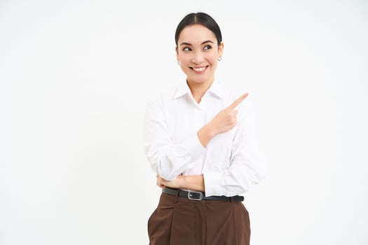 Image of asian businesswoman points finger to the right, shows advertisement, demonstrates banner, white background photo