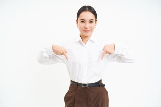 Confident smiling businesswoman, asian office lady points fingers down, shows advertisement, promo offer below, white background photo