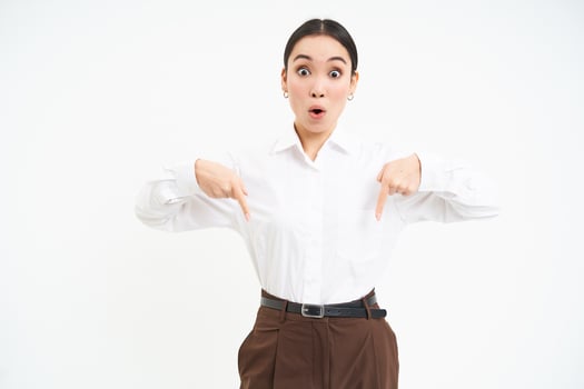Image of korean businesswoman points finger at banner, shows advertisement, white studio background photo