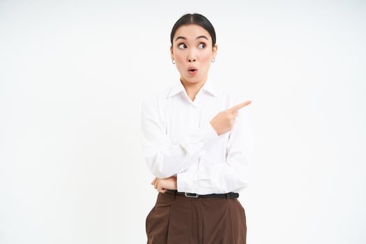 Image of korean businesswoman points finger at banner, shows advertisement, white studio background photo